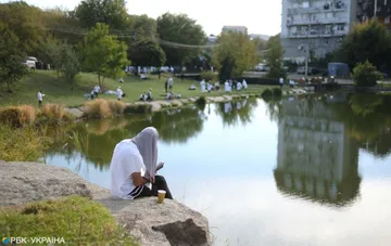 A Hasid in white prayer by a pond during Rosh Hashana pilgrimage in Ukraine