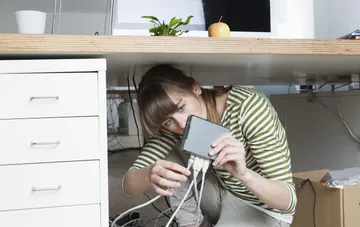A technician connects cables to a network switch under a desk amid connectivity disruptions in UTELS and Pavutyna networks after an attack on the capital's data center