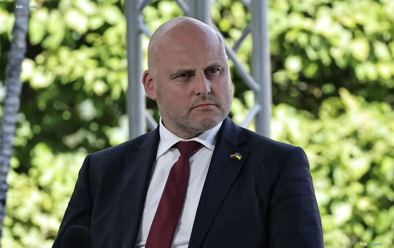 Prime Minister of Latvia in a suit with a Ukrainian flag pin on his lapel against green foliage — details of the vote on lifting sanctions against Usmanov and Fridman