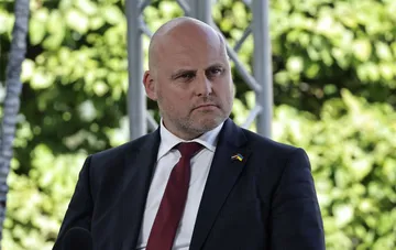 Prime Minister of Latvia in a suit with a Ukrainian flag pin on his lapel against green foliage — details of the vote on lifting sanctions against Usmanov and Fridman