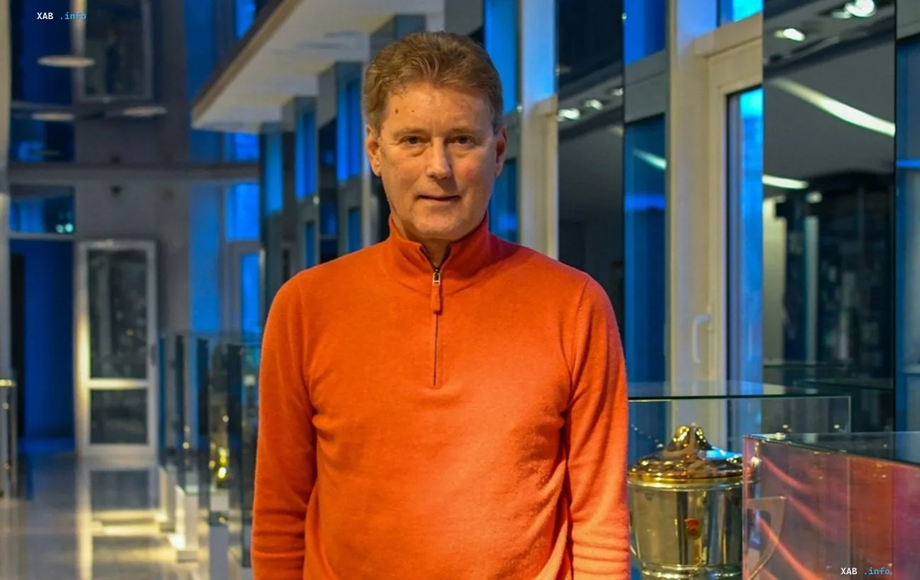 Leonid Buriak in an orange sweater beside a football trophy marking the 50th anniversary of the win over Bayern Munich