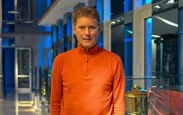 Leonid Buriak in an orange sweater beside a football trophy marking the 50th anniversary of the win over Bayern Munich