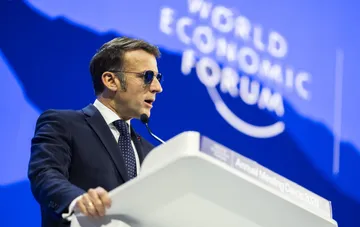 Emmanuel Macron in sunglasses speaks at the World Economic Forum podium in Davos, criticizing the US stance on Gaza