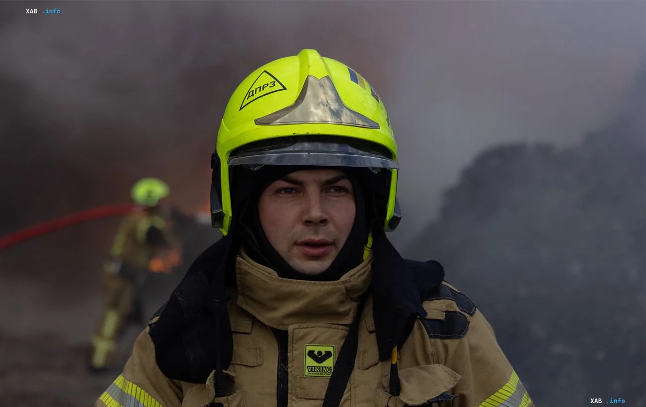 Firefighter in yellow helmet at the scene of a drone attack on Kyiv amid smoke