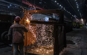 A worker in protective gear performing welding at a metallurgical plant, illustrating the current state and risks for the industry in the absence of government support