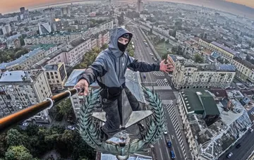 Roofer with a selfie stick on the star of Kharkiv's 'House with a Spire' at sunrise