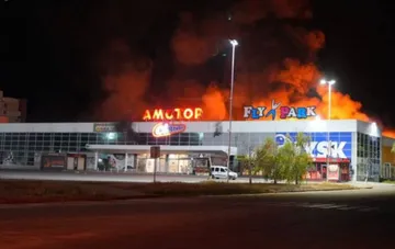 Fire at the Amstor shopping mall in Zaporizhzhia after a strike: flames and smoke rise above the roof with the AMSTOR and FLY PARK signs