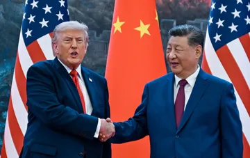 Дональд Трамп и Си Цзиньпин пожимают руки на фоне американских и китайских флагов во время исторической встречи в Вашингтоне