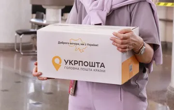 A person holds a box with the Ukrposhta logo at a city post office when sending a parcel under the priority rule