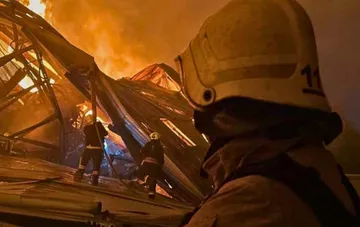 Firefighters extinguish a fire on the damaged roof of the Parkovy KVC in Kyiv after a drone strike