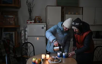 Residents of Teremky in winter clothes warming up with hot tea in a cold, unheated apartment