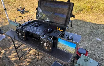 Feldstation eines UAV-Operators mit mehreren Fernbedienungen, Monitoren und Laptop zur Steuerung einer Drohnengruppe über Glasfaser