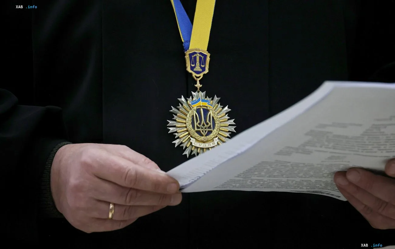 Судейская награда с гербом Украины и весами правосудия на груди человека в черном, держащего документы — визуальный контекст рейдерской сети судей по версии НАБУ