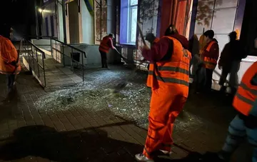 Arbeiter in orangen Warnanzügen fegen zerbrochenes Glas aus dem Hof eines Krankenhauses in Odessa nach einem nächtlichen Angriff