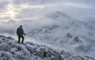 Wanderer mit Rucksack auf dem schneebedeckten Berg Pop Ivan in den Karpaten bei Frost und erstem Schnee