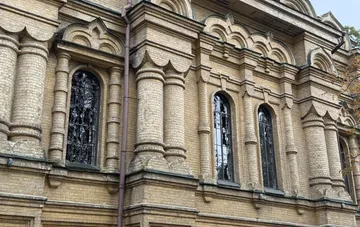 Фасад старейшей церкви Виноградара в Киеве из жёлтого кирпича 1906 года после вражеской атаки: повреждённые арочные окна и декоративные колонны