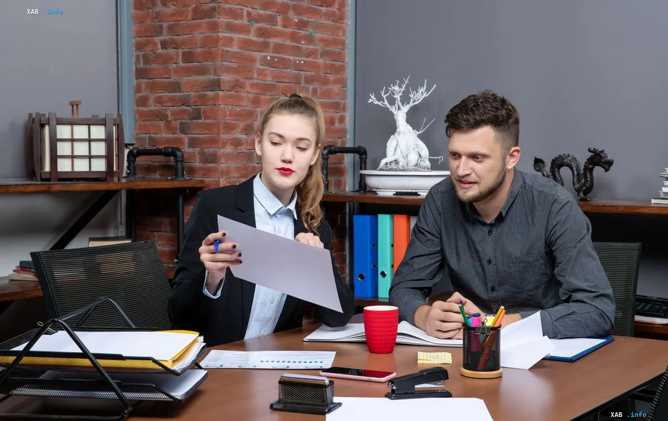 Kollegen prüfen ein Stellenangebot und Gehaltsbedingungen während eines Einstellungsgesprächs mit Dokumenten auf dem Tisch
