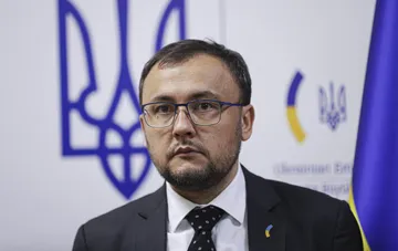 Посол Украины в Польше на фоне государственного герба и флага во время брифинга о росте числа нападений на украинцев