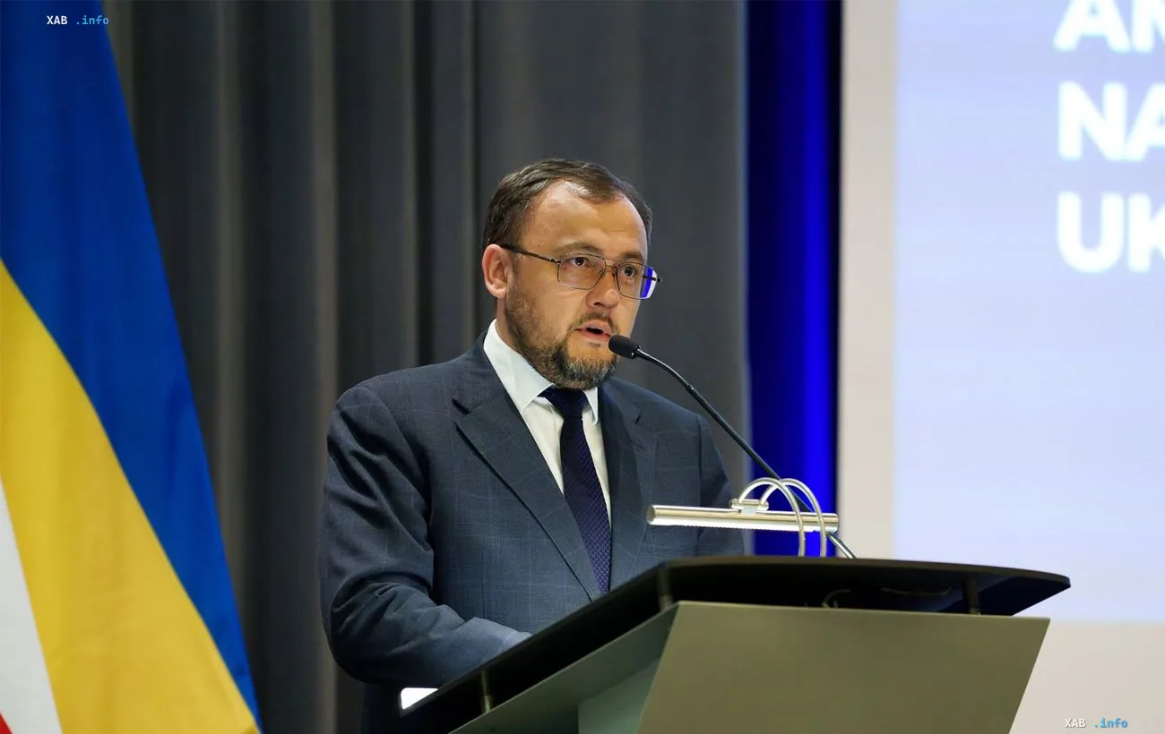 Украинский посол выступает за трибуной с микрофоном на фоне флага Украины, объясняя причины сокращения числа украинцев под временной защитой в Польше