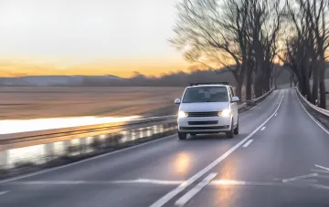 Car with headlights on during the day on the road