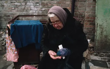 Пожилой человек считает монеты на столе