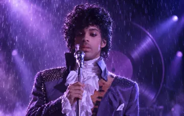 Музыкант Принс выступает на сцене с группой The Revolution во время исполнения Purple Rain