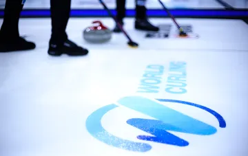 Логотип World Curling на льду и спортсмены с щетками для керлинга