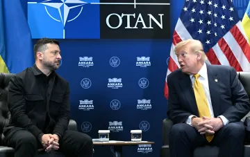 Президент Украины Владимир Зеленский и президент США Дональд Трамп ведут диалог на фоне символики НАТО и американского флага во время саммита в Анкаре