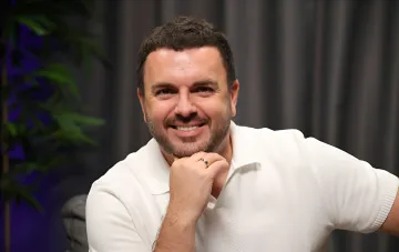 Ukrainian TV host Grigoriy Reshetnik in a white shirt smiling during an interview in the studio
