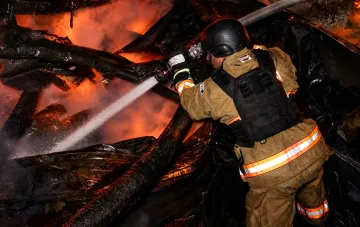 Firefighter in protective gear extinguishes a large fire at a drone crash site