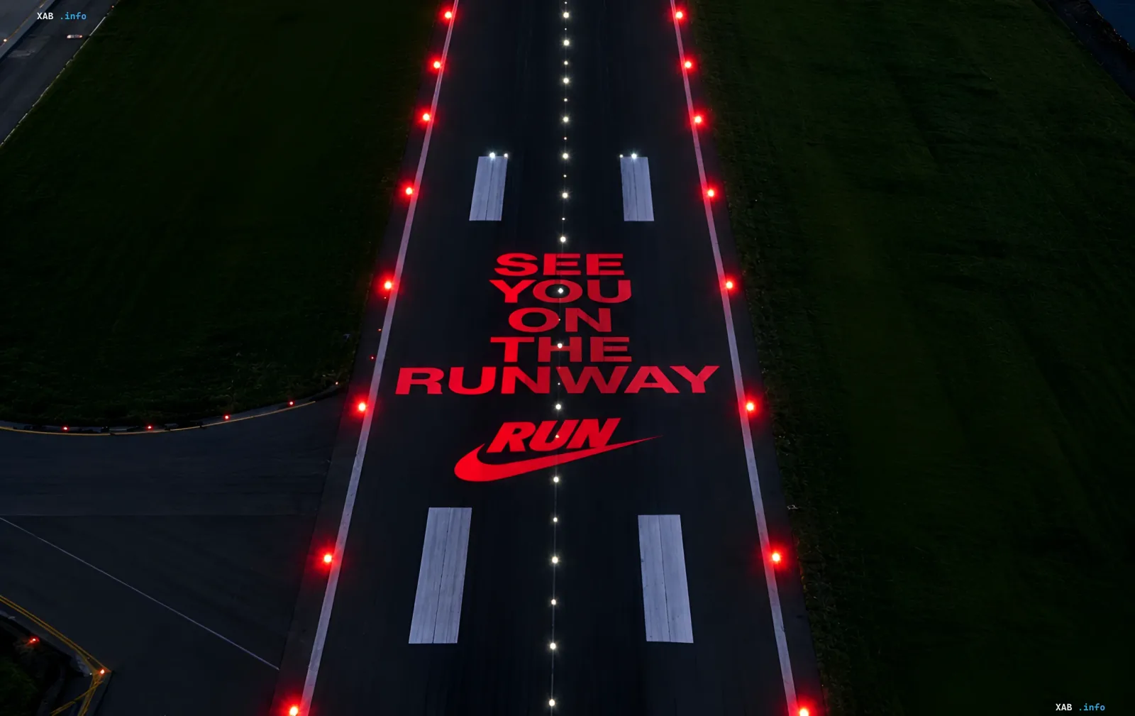Mit rotem Licht beleuchtete Landebahn am Flughafen London mit Nike-Branding vor dem Nachtlauf