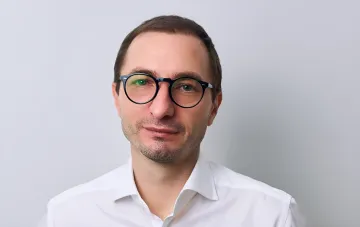 Man in glasses and a white shirt against a light background, expert oncologist