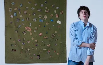 Designer Sean McGirr posiert neben einer Textil-Kunstinstallation