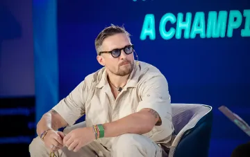 Олександр Усик у світлій сорочці та окулярах виступає на конференції