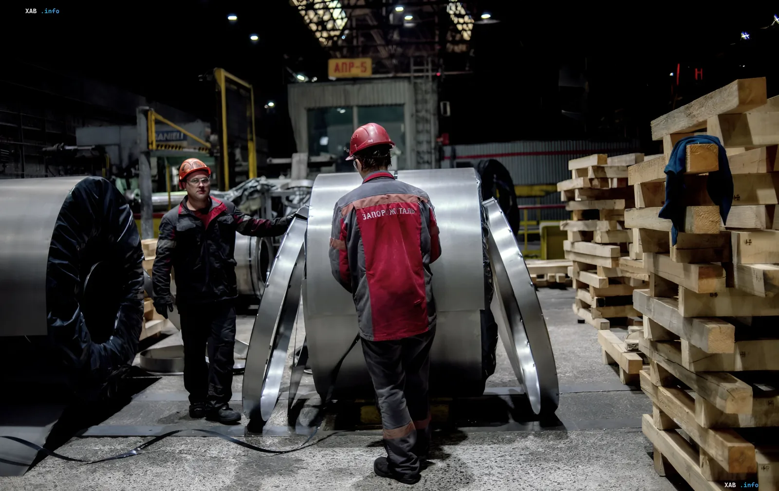 Two metallurgists in hard hats inspect steel coils at the Zaporizhstal plant