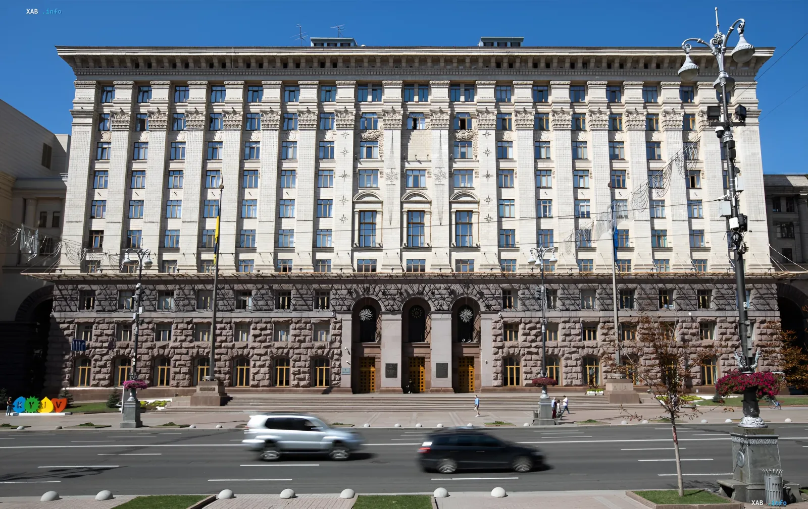 Facade of the Kyiv City State Administration building against a clear sky with passing cars