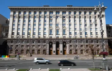 Fassade des Gebäudes der Kiewer Stadtverwaltung vor klarem Himmel mit vorbeifahrenden Autos