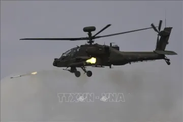Военный ударный вертолет AH-64 Apache в полете запускает ракету в ходе учений