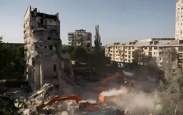 Destroyed multi-story residential building and construction machinery at a shelling site in Kyiv