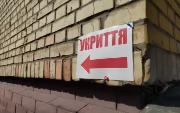 Shelter sign with a red arrow on a brick wall of a Kyiv building