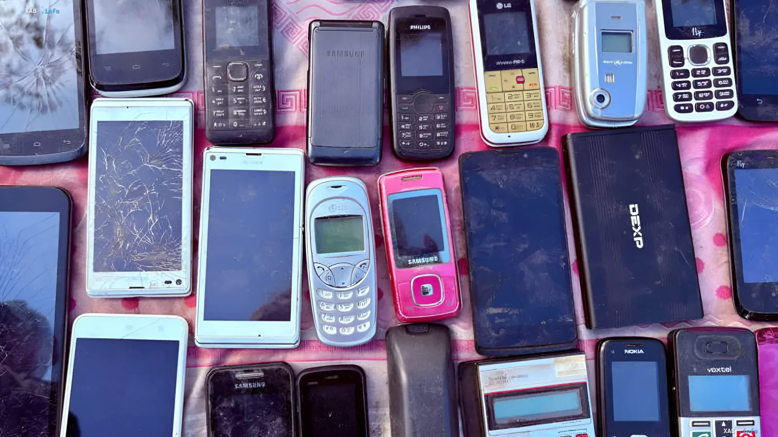 Старые кнопочные телефоны Nokia и Samsung лежат на розовой поверхности