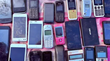 Старые кнопочные телефоны Nokia и Samsung лежат на розовой поверхности