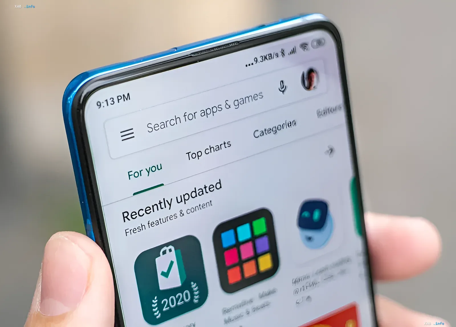 смартфон в руке с открытым магазином приложений Google Play на экране