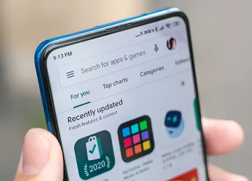 смартфон в руке с открытым магазином приложений Google Play на экране