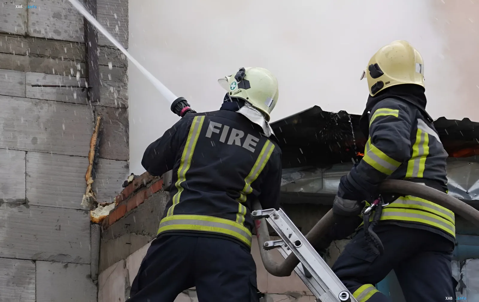 Firefighters extinguish a burning building following an enemy drone attack on infrastructure