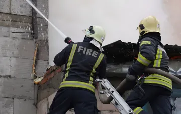 Firefighters extinguish a burning building following an enemy drone attack on infrastructure