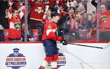 Hockey player in a red Florida jersey celebrates a goal near the boards