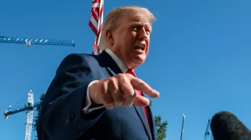 Дональд Трамп в синем костюме энергично жестикулирует на фоне синего неба