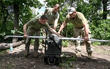 Ukrainian military personnel prepare an airplane-type reconnaissance drone for launch in a forest belt