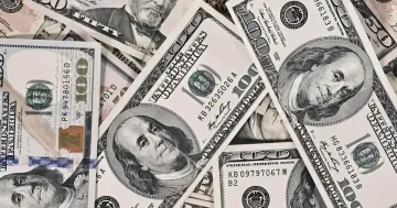A pile of US one hundred dollar bills lying on a table